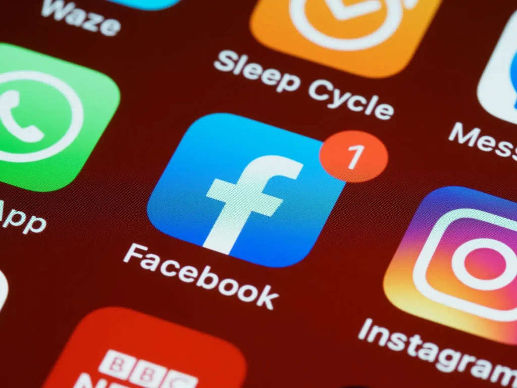 Écran de smartphone affichant des icônes d'applications de réseaux sociaux, dont Facebook avec une notification ainsi qu'Instagram et WhatsApp.