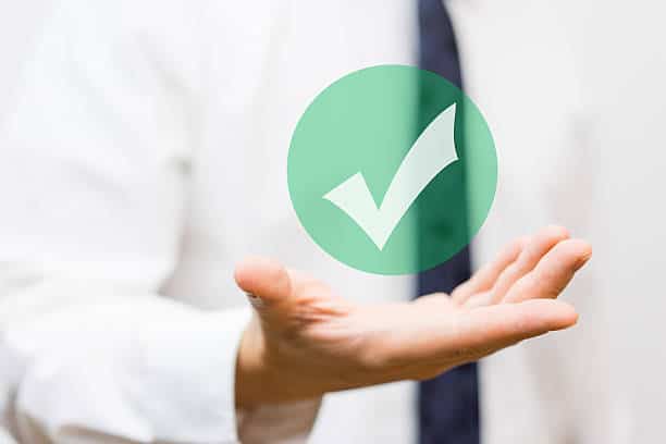 Homme d'affaires tendant la main avec une icône de validation verte affichée au-dessus, symbolisant l'approbation ou la réussite